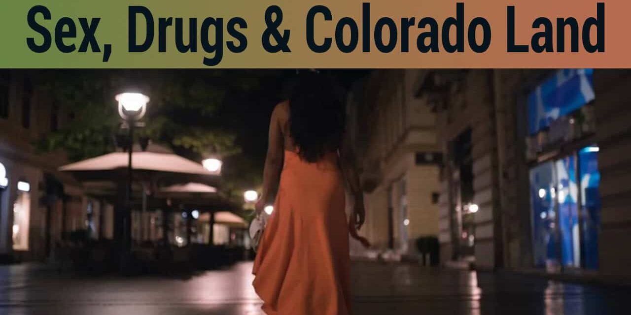 Woman walking alone at night in an urban area, illuminated by streetlights, representing themes of controversy surrounding sex work, drugs, and land disputes in Colorado.