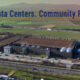An aerial view of a large 5G AI data center surrounded by green fields and infrastructure, highlighting the role of technology hubs in community development and connectivity.